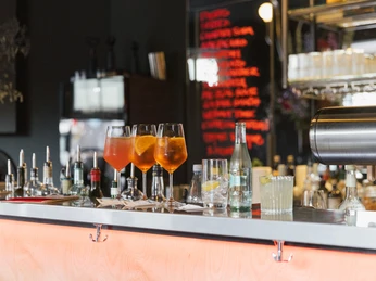 OFF Bar Getränke und Gläser auf einer Bar mit betonten orangenen Lichtern und Hintergrundobjekten.Drinks and glasses on a bar with accentuated orange lights and background objects.