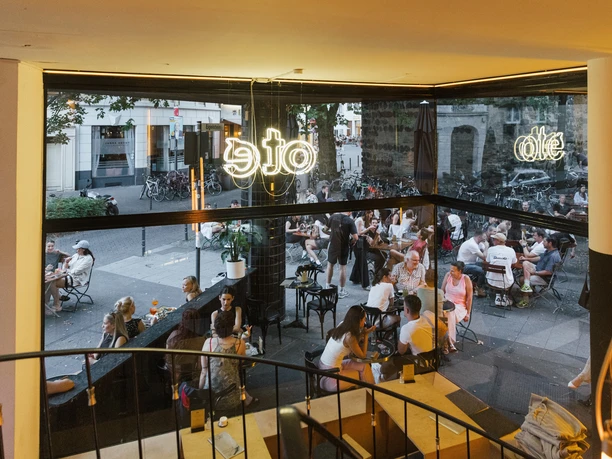 Oté People enjoying a cozy get-together in a lively street café in the evening.
