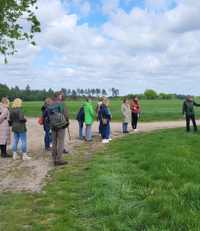 Lehrerfortbildung am Theikenmeer_Naturpark Schule Bernhardschule ©Naturpark Hümmling Gruppe von Lehrkräften steht im Grünen, hört einem Vortragenden vor einer Infotafel am Weg zu.
