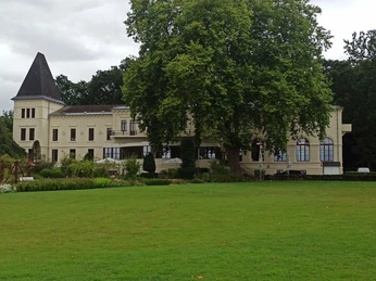 Altes-Kurhaus-Bad-Zwischenahn.jpg Historisches Altes Kurhaus in Bad Zwischenahn, umgeben von üppigem Grün und majestätischen Bäumen.