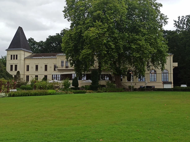 Altes-Kurhaus-Bad-Zwischenahn.jpg Historisches Altes Kurhaus in Bad Zwischenahn, umgeben von üppigem Grün und majestätischen Bäumen.