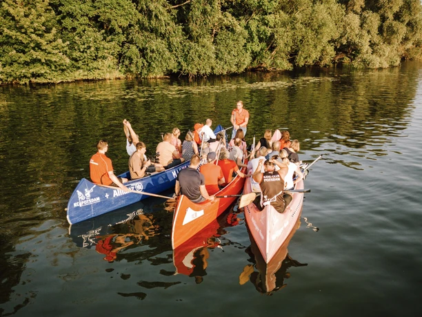 SPORT SPEAKER Kanu Team Event Seeminar 01_Martin Schneegang ganscool.media.jpg Mehrere gefüllte Kanus auf dem Wasser beim Sport Speaker Team Event