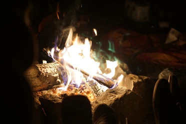 Feuer_160904_0031_DSC01446_RG.JPG Lagerfeuer mit brennenden Holzscheiten in einer von Steinen umrandeten Feuerstelle