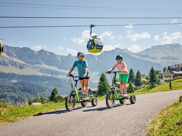 Zwei Mädchen am Bikeboard fahren auf der Stockhütte.