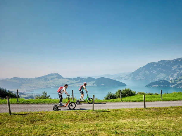 Bikeboard-Stockhütte (1).jpg Zwei Freundinnen am Bikeboard fahren mit Aussicht auf den Vierwaldstättersee von der Stockhütte nach Emmetten.