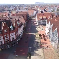 Blick vom Stadtkirchturm Richtung Lange Str. - R. Kranz.jpg Luftaufnahme einer historischen Stadt mit roten Ziegeldächern, einer Fußgängerzone und Fachwerkhäusern.