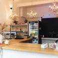 Das Neandertal No. 1 - Café und Events in Erkrath Ein helles Café mit Kronleuchtern, Holztresen und Kühlvitrinen, das eine warme Atmosphäre ausstrahlt.