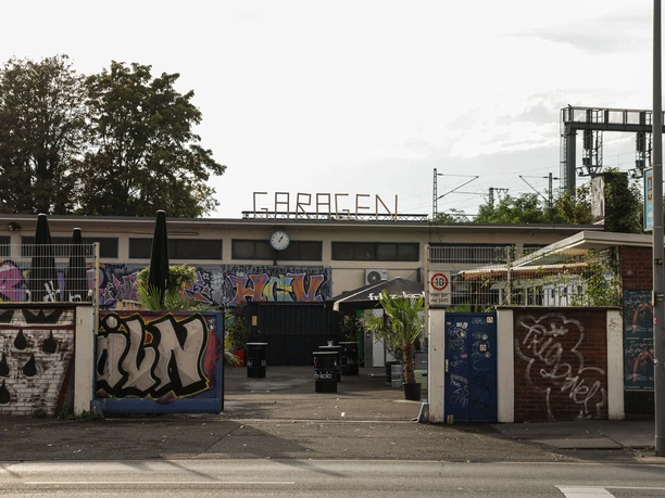 Garagen Club Eingang zum Garagen-Club in Köln, Graffiti an den Wänden, urbanes Flair bei bewölktem Himmel.