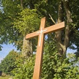 Bültekreuz aus Holz vor Bäumen und blauem Himmel in Pömbsen.