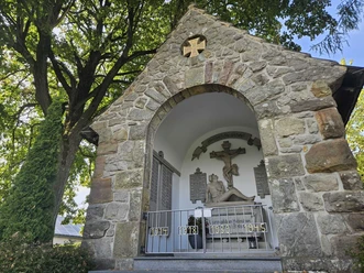 Ehrenmal aus Stein, umgeben von Bäumen in Pömbsen.
