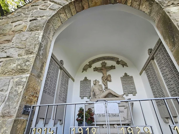 Ehrenmal aus Stein in Pömbsen, gewidmet den Gefallenen der Weltkriege, mit Gedenktafel und Kreuz.