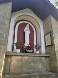 Die Banneux-Kapelle in Pömbsen, mit Statue der "Jungfrau der Armen" neben der Kirche.