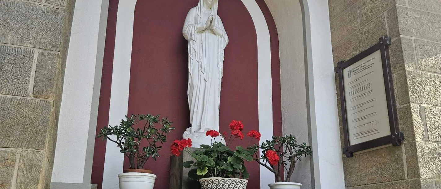 Die Banneux-Kapelle in Pömbsen, mit Statue der "Jungfrau der Armen" neben der Kirche.
