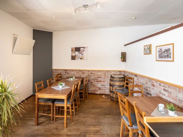 Barntrup-Sonneborn-Dorfladen-Sonneborn-Teutoburger-Wald-LTM-GmbH-D-Ketz-104.jpg Heller Raum eines Dorfladens mit Holztischen, Stühlen und Backsteinwand, dekoriert mit Bildern.