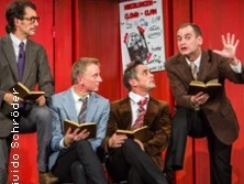 Vier Männer in Anzügen sitzen auf Stühlen, während sie in Büchern lesen und diskutieren.