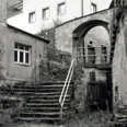 Historisches Foto vom Malerwinkel Steinerne Treppen führen zu einem historischen Torbogen inmitten verwitterter Backsteinstrukturen.