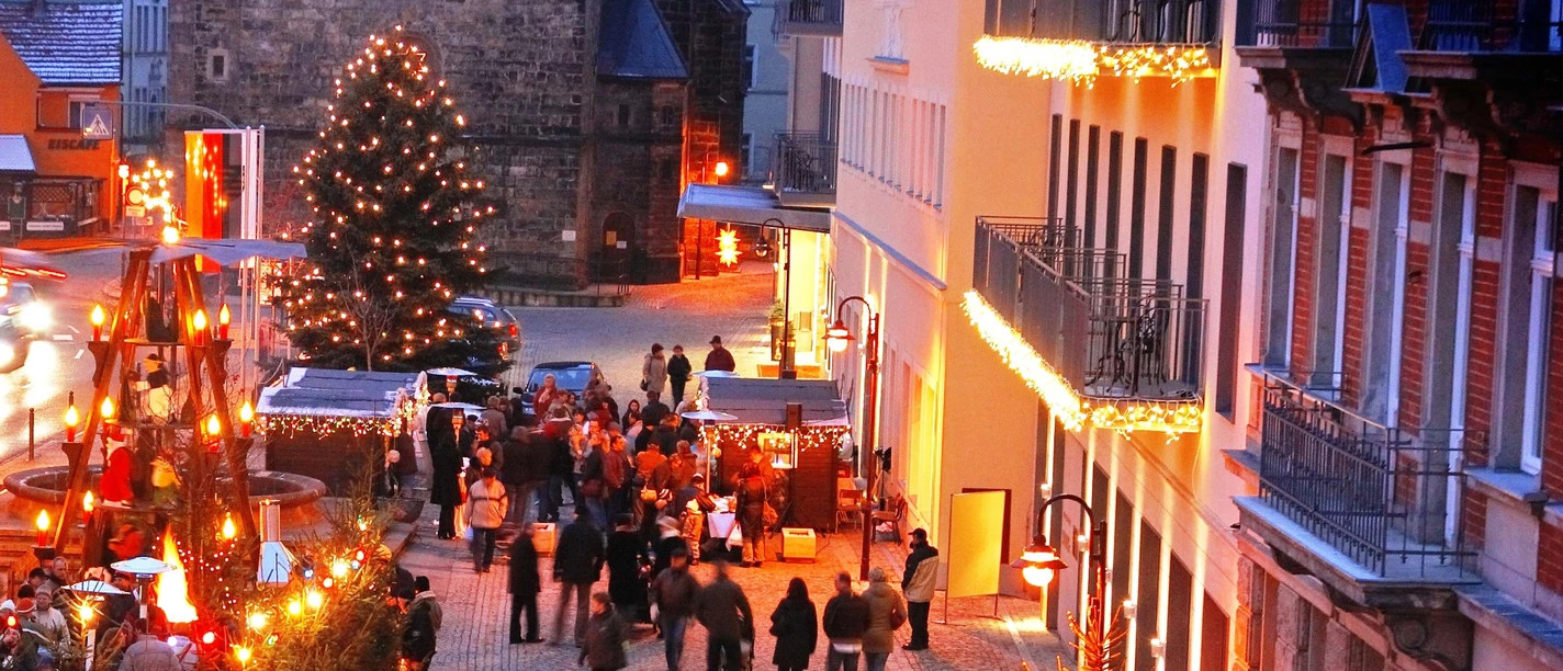 Bad Schandauer Adventsbummel Weihnachtlich beleuchtete Straße in Bad Schandau mit geschmücktem Baum und Menschen beim Adventsbummel.