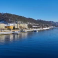 Blick auf Bad Schandau Flussufer mit pastellfarbenen Gebäuden, bewaldeten Hügeln und blauem Himmel in winterlicher Atmosphäre.Riverside with pastel-colored buildings, wooded hills and blue skies in a wintry atmosphere.Riverside s pastelově zbarvenými budovami, zalesněnými kopci a modrou oblohou v zimní atmosféře.Riverside z pastelowymi budynkami, zalesionymi wzgórzami i błękitnym niebem w zimowej atmosferze.Riverside met pastelkleurige gebouwen, beboste heuvels en blauwe luchten in een winterse sfeer.Riverside con edifici dai colori pastello, colline boscose e cielo azzurro in un'atmosfera invernale.