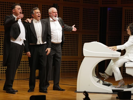 luciano_presse.jpg Drei Männer in Anzug halten sich singend neben einem weißen Klavier im Arm