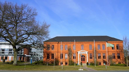 Rathaus Osterholz-Scharmbeck Rotes Backsteingebäude mit vier Fahnenmasten davor und links ein moderner, runder Anbau mit viel Glaselementen