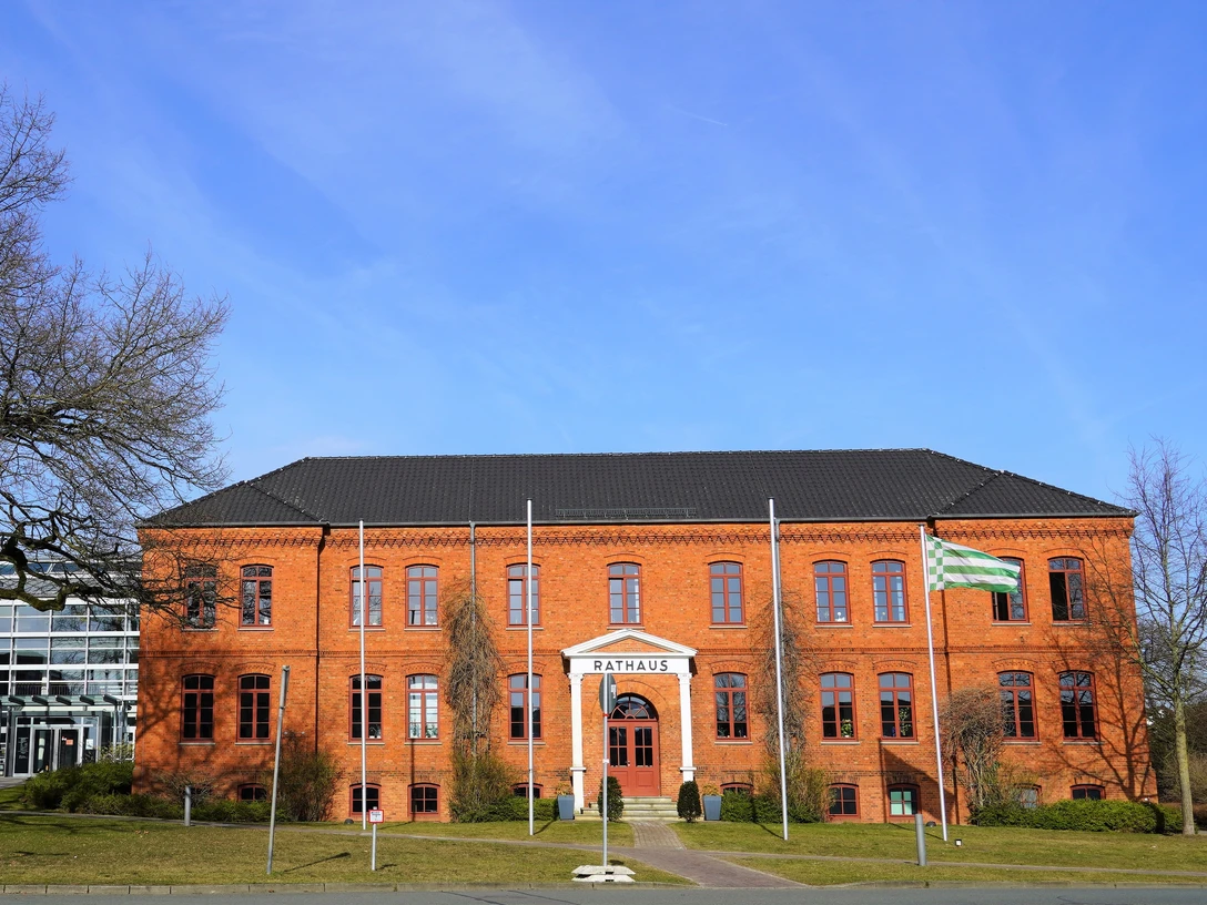 Rathaus Osterholz-Scharmbeck Rotes Backsteingebäude mit vier Fahnenmasten davor und links ein moderner, runder Anbau mit viel Glaselementen