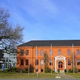 Rathaus Osterholz-Scharmbeck Rotes Backsteingebäude mit vier Fahnenmasten davor und links ein moderner, runder Anbau mit viel Glaselementen