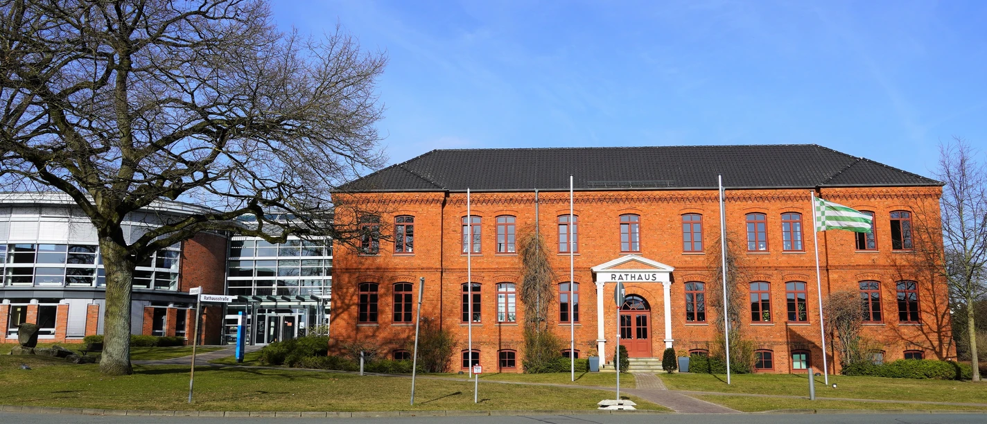 Rathaus Osterholz-Scharmbeck Rotes Backsteingebäude mit vier Fahnenmasten davor und links ein moderner, runder Anbau mit viel Glaselementen