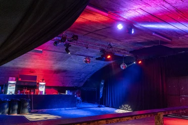 Vue intérieure du Hangar Five avec bar, jeux de lumière et piste de danse à Goms