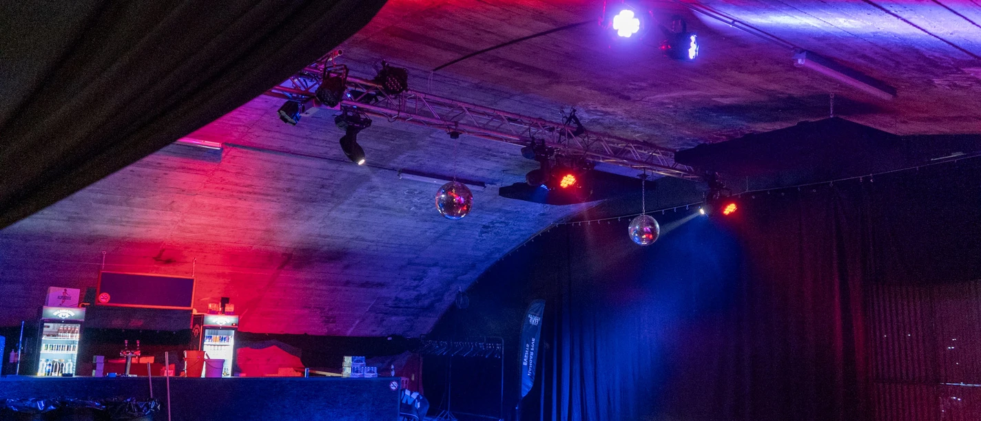 Vue intérieure du Hangar Five avec bar, jeux de lumière et piste de danse à Goms