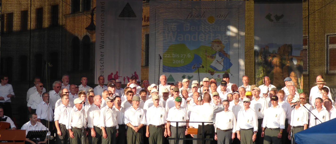 Bergsteigerchor beim Tag des Wanderns 2016 Eine große Gruppe von Sängern in weiß gekleidet steht auf einer offenen Bühne beim Bergsteigerchor.
