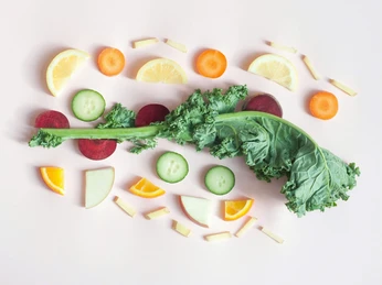 Gemuese-Gruenkohl.jpg Grünkohl mit Zitronenscheiben, Gurken, Möhren und Apfelstücken auf hellen Hintergrund.