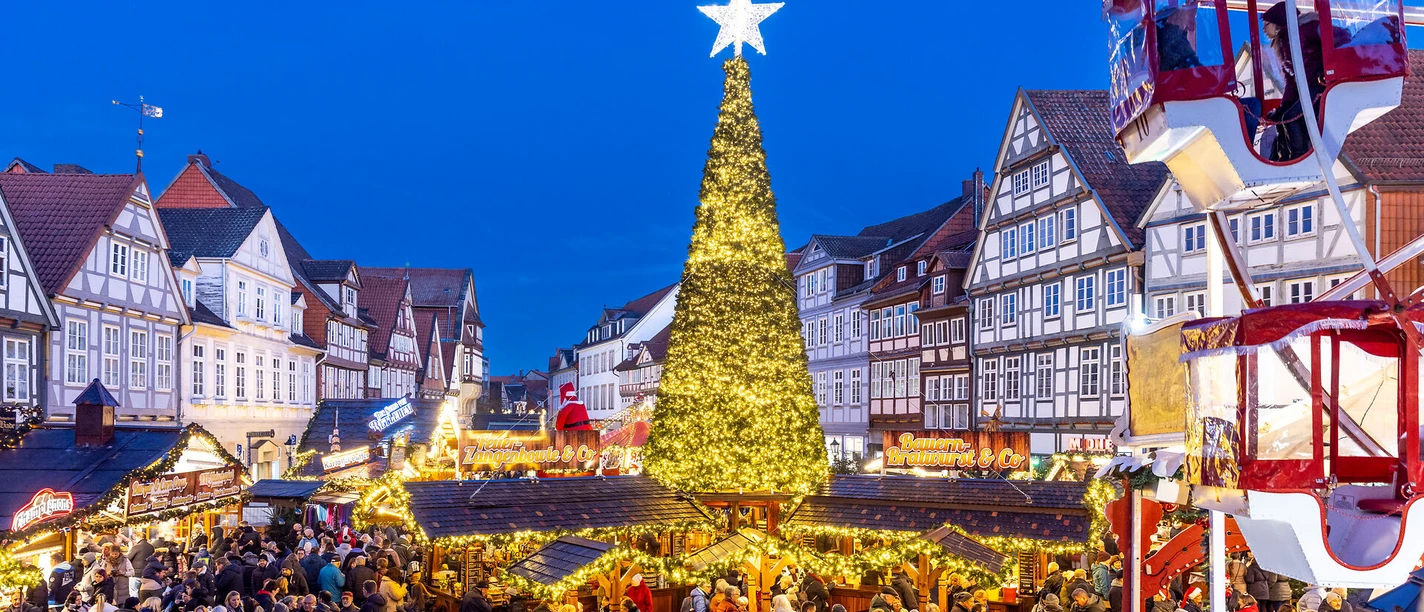 Weihnachtsmarkt Celle Kerstmarkt in Celle: Een gloeiende kerstboom omringd door vakwerkhuizen en mensenmassa's.