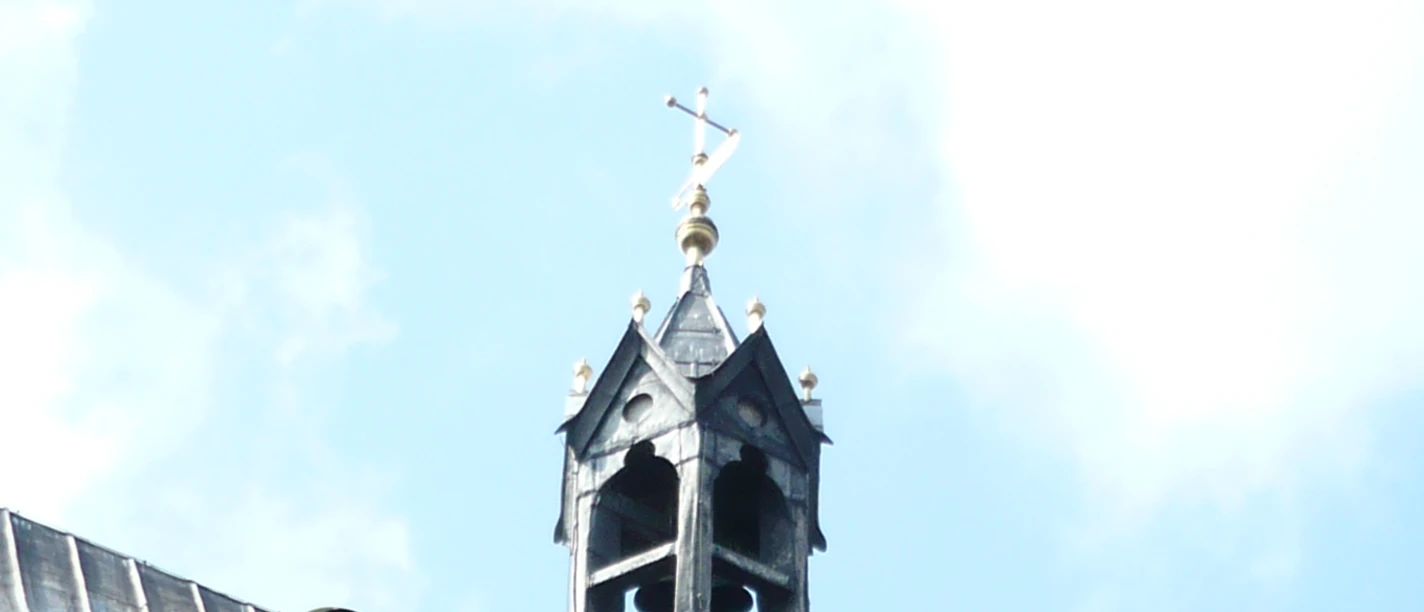 6 Stiftskirche.JPG Glockenturm der Stiftskirche mit steinernem Bogen und mittelalterlichem Mauerwerk unter blauem Himmel.