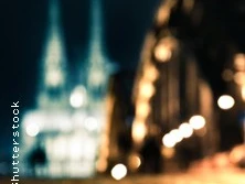 Zwei unscharfe, nächtlich beleuchtete Kirchtürme und eine erleuchtete Straße im Vordergrund.