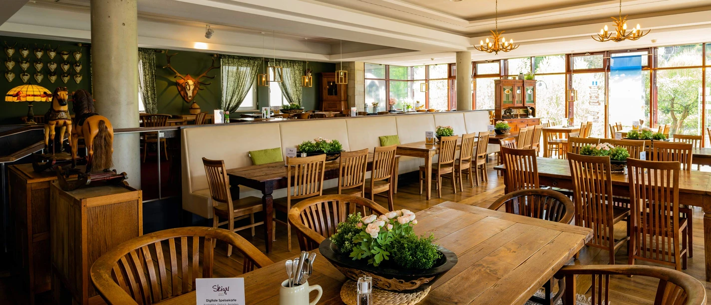 Inviting bistro atmosphere with wooden furniture, elegant lighting and a view of lush nature.