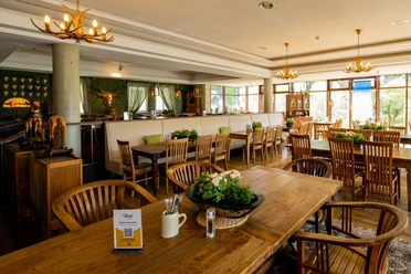 Panorama Bistro im Hotel Rathener Hof Inviting bistro atmosphere with wooden furniture, elegant lighting and a view of lush nature.