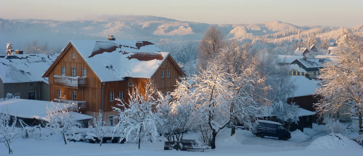 Ferienhaus Winterbergblick Ferienhaus in verschneiter Winterlandschaft an einem klaren Tag, umgeben von schneebedeckten Bäumen.