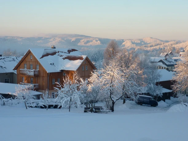 Ferienhaus Winterbergblick Ferienhaus in verschneiter Winterlandschaft an einem klaren Tag, umgeben von schneebedeckten Bäumen.