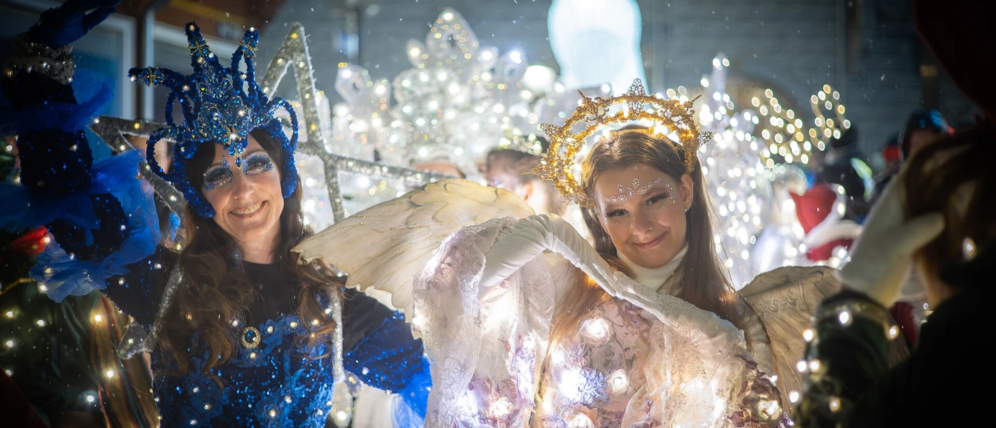 Lichterfiguren Light effects illuminate two people in imaginative costumes at a night-time event.