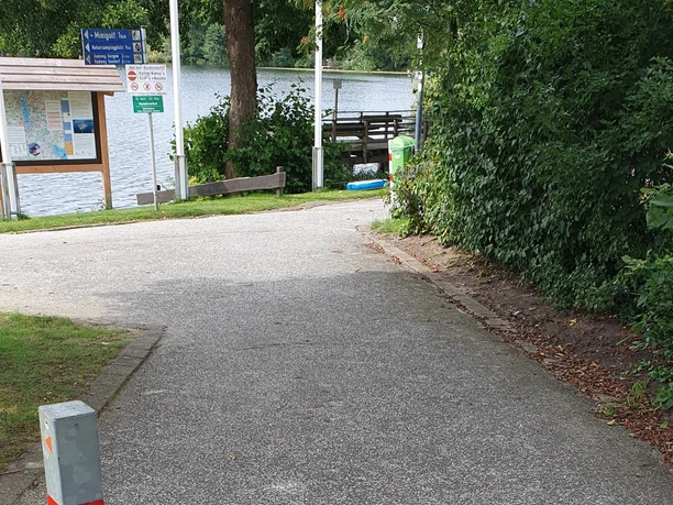 Zugang zum Wanderweg Leicht abschüssiger Zugang zum Wanderweg. Der Untergrund ist asphaltiert.