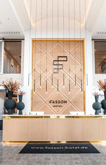 Empfang Heller Empfangsbereich mit moderner Holzoptik, goldenen Akzenten und hohen Regalen voller Dekoration.