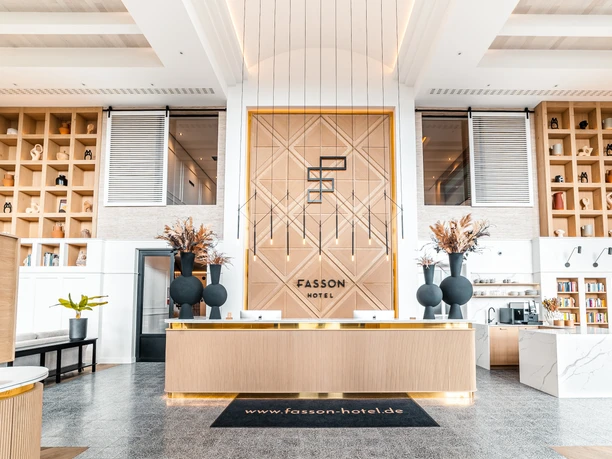 Empfang Heller Empfangsbereich mit moderner Holzoptik, goldenen Akzenten und hohen Regalen voller Dekoration.