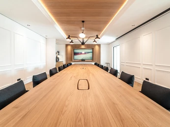 Konferenzraum Stirnseite Moderner Konferenzraum mit großem Holztisch, schwarzen Stühlen und Bildschirm an der Stirnwand