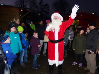 Sinterklaas zwaait op de Sinterklaasmarkt, omringd door kinderen en bezoekers.