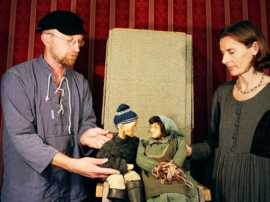 figurentheater-ernst-heiter-vom-fischer-und-seiner-frau.jpg Zwei Personen führen Holzpuppen im Märchen „Vom Fischer und seiner Frau“ vor rotem Bühnenhintergrund.