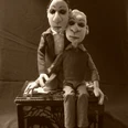 seifenblasen-theater-hannes-und-paul.jpg Zwei Puppenfiguren sitzen eng auf einer Kiste und blicken ernst in die Kamera.