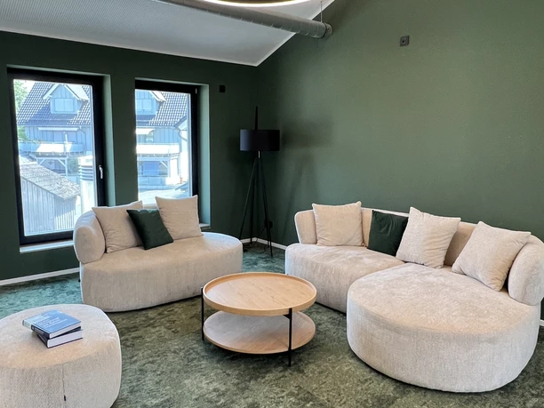 Denkschmiede Moderner Loungebereich der Denkschmiede mit grünen Wänden und hellen Sofas