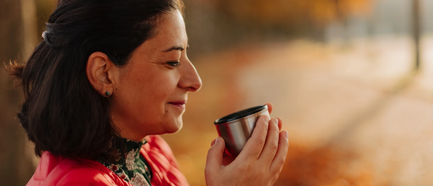 Teestunde Eine Frau genießt Tee aus einer Thermoskanne im herbstlichen Park Sanssouci