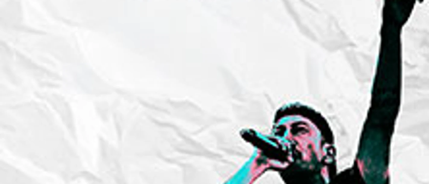 Ein Sänger tritt auf einer Bühne auf, in der linken Hand ein Mikrofon, rechte Hand hochgestreckt.