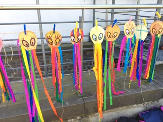 Drachenbau Bunte selbst gebastelte Drachen mit langen Papierstreifen hängen an einer Leine.